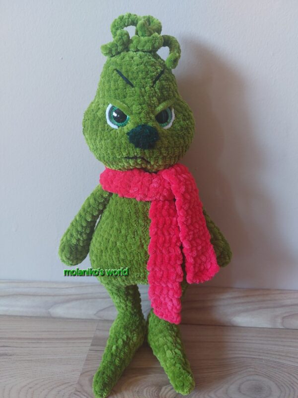 Grinch, amigurumi figura, zöld zseníliafonálból horgolt, piros sállal, morcos arckifejezéssel és bozontos textúrával