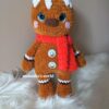 Mézi, amigurumi mézeskalács figura, zseníliafonálból horgolt, piros sállal, fehér cukormáz díszítéssel és ünnepi gombokkal.