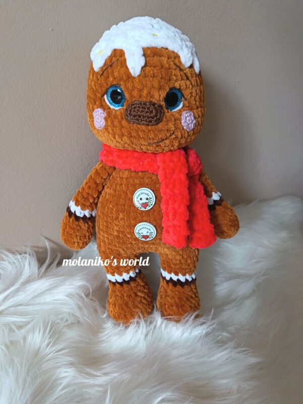 Mézi, amigurumi mézeskalács figura, zseníliafonálból horgolt, piros sállal, fehér cukormáz díszítéssel és ünnepi gombokkal.